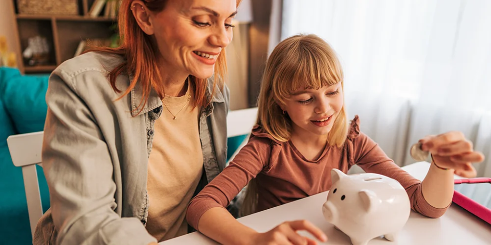 Eine Mutter erklärt ihrer Tochter das Sparen und die Vorteile sowie Funktionen ihres Kinderkontos. 