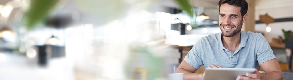 Junger Mann am Schreibtisch mit Tablet