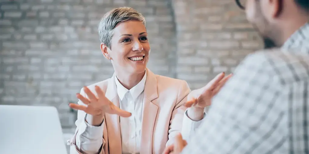 Eine Beraterin unterhält sich mit einem Mann innerhalb einer Anlageberatung.