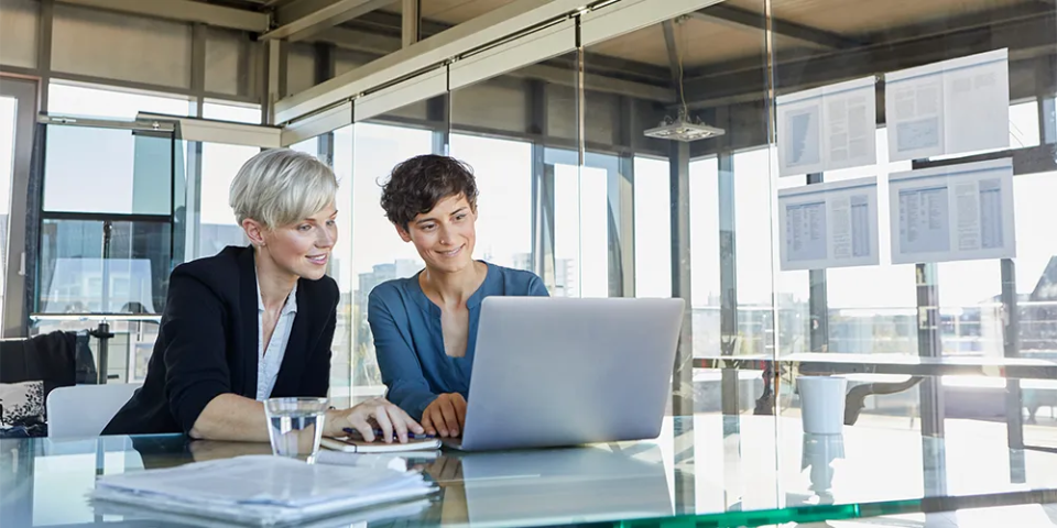 Zwei Frauen sitzen vor dem Laptop.