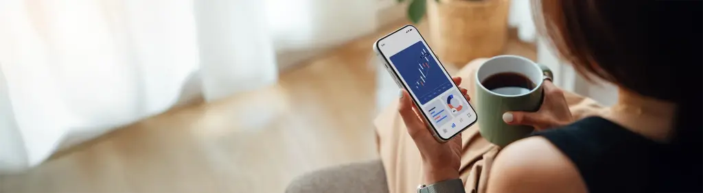 Eine Person schaut sich am Handy die Wertentwicklung ihres Anleihen-ETFs an.