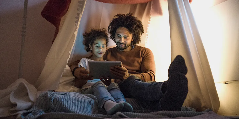 Ein Vater erklärt seinem Sohn die Steuern bei einer Geldanlage für Kinder.