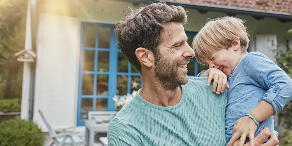 Ein Vater hält seinen Sohn auf dem Arm, für den er mit einer Geldanlage für Kinder vorgesorgt hat.