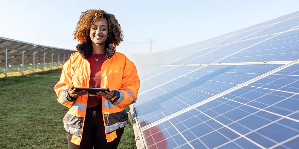 Eine Frau steht vor einer Solaranlage, ein Projekt, welches durch Impact Investing unterstützt wird.