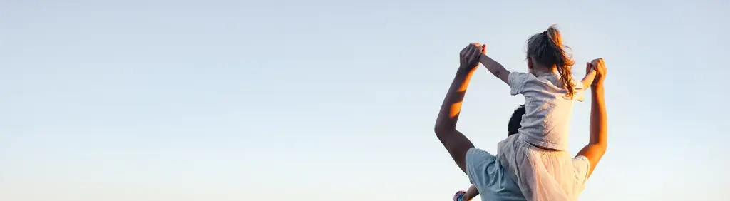 Ein Vater trägt seine Tochter auf den Schultern und streckt ihre Hände in den Himmel - mit dem Junior-Depot hat er richtig vorgesorgt. 