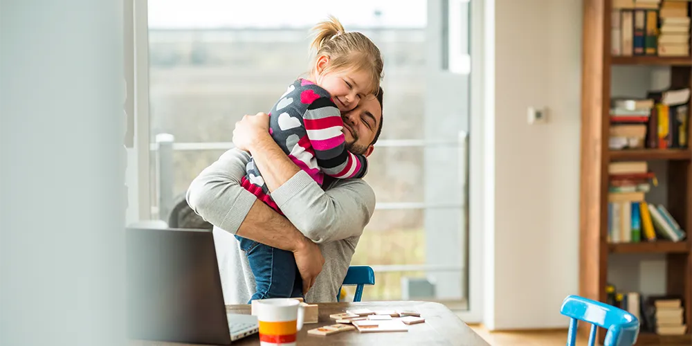 Ein Vater umarmt seine Tochter, für die er gerade eine Kindervorsorge abgeschlossen hat. 