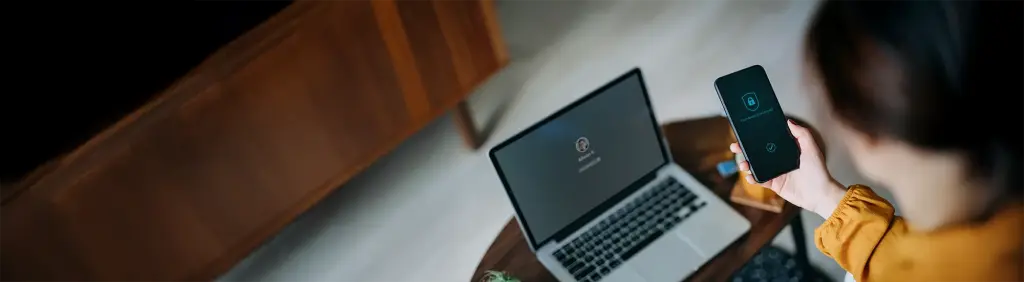 Person prüft die Cyberversicherung am Handy und am Laptop