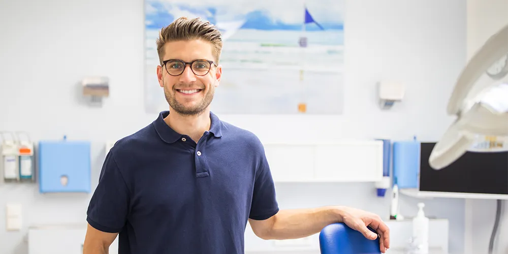 Ein junger Zahnarzt fragt sich, was eine Berufsunfähigkeitsversicherung kostet. 