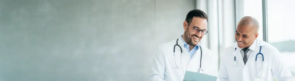 Zwei Mediziner unterhalten sich über die passende Krankenversicherung für Ärztinnen und Ärzte.