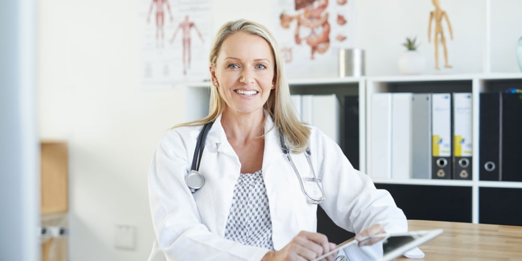 Ärztin in Praxis am Schreibtisch | MLP