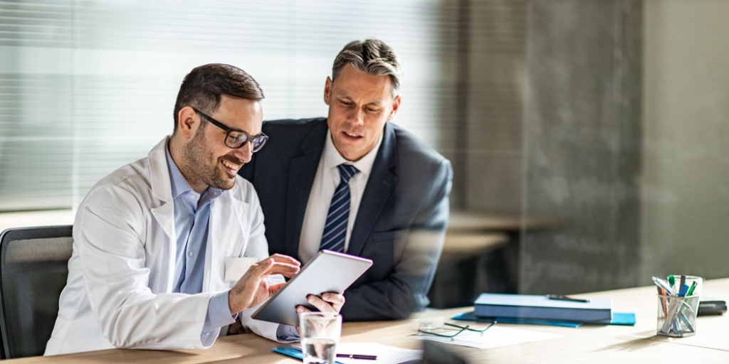 Arzt und Investor gemeinsam am Schreibtisch / MLP