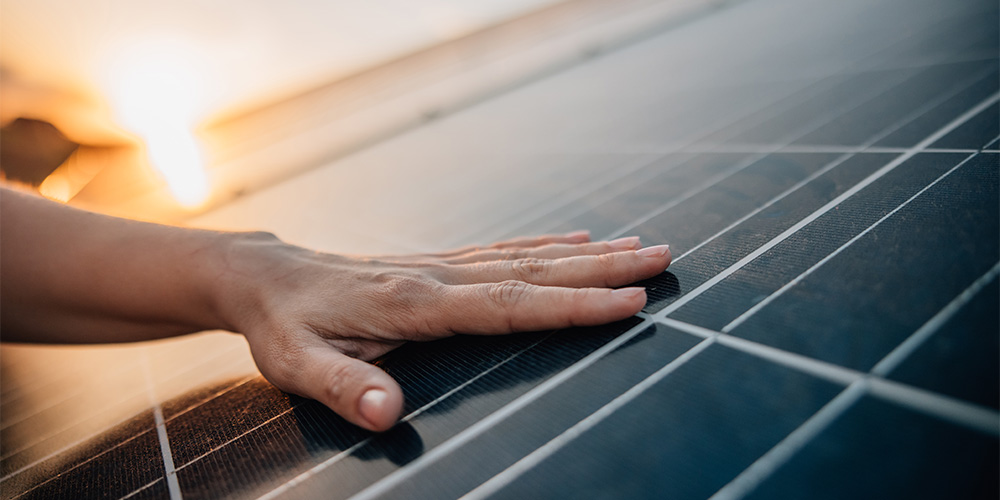 menschliche Hand auf einem Solarpanel