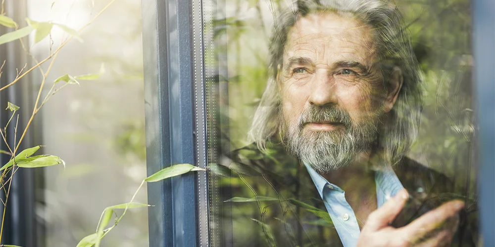 Älterer Mann, aus dem Fenster schauend