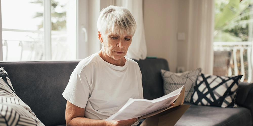 Eine Frau sitzt auf dem Sofa und informiert sich über den Gender Pension Gap und ihre Altersvorsorge.