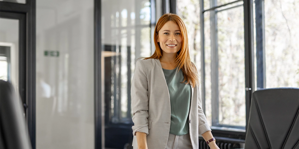 Eine junge Frau steht im Büro und hat sich über den Gender Pay Gap und ihre Altersvorsorge informiert.